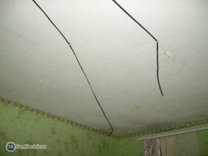 Прокладка кабеля по потолку, кабель справа - под люстру, слева - входит в гипсокартонную стену и опускается вниз к розетке.